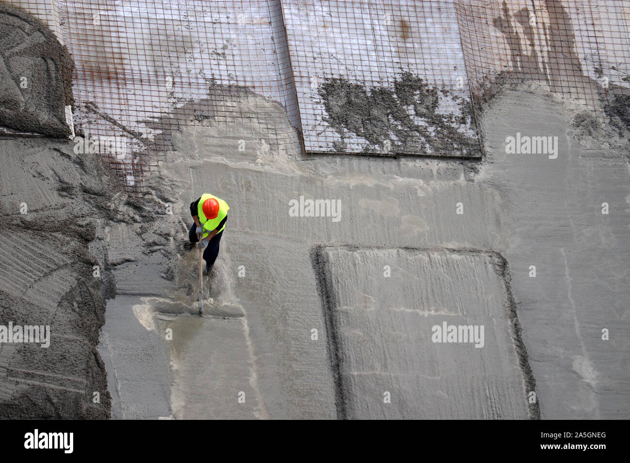 Verter hormigón para los trabajadores en el lugar de construcción, vista desde la parte superior. Instalación de soportes para los cimientos del edificio, colocación de losas de hormigón Foto de stock
