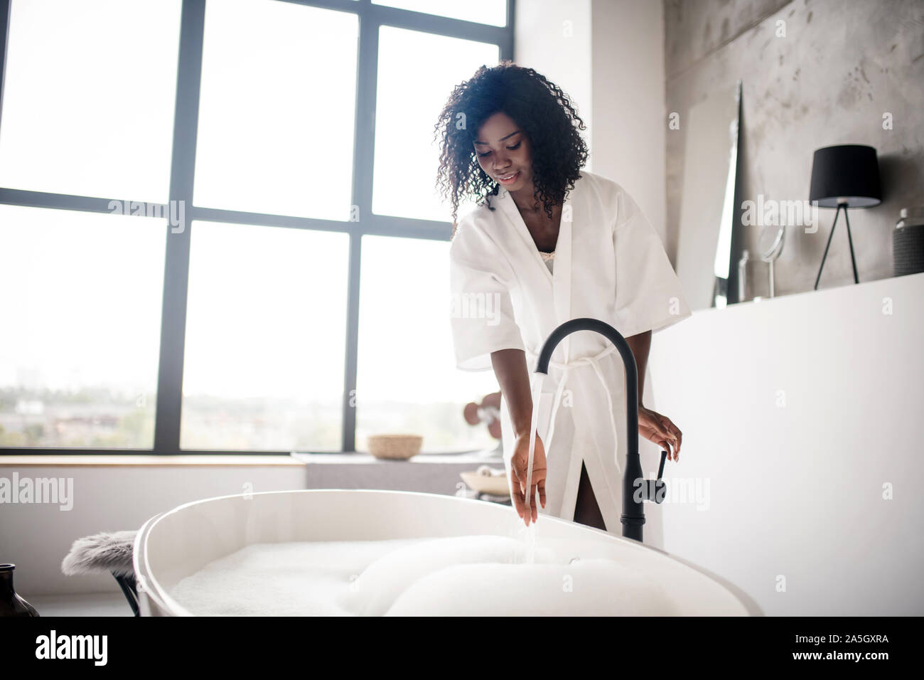 Rizado mujer preparando de piel oscura con espuma de baño Foto de stock