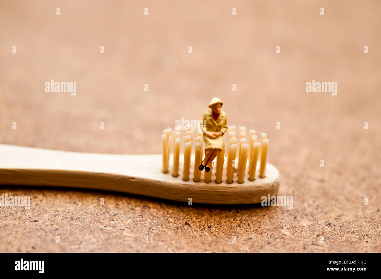 Figurillas en miniatura sentado en un cepillo de dientes de bambú - concepto de consumidor consciente ecológico Foto de stock