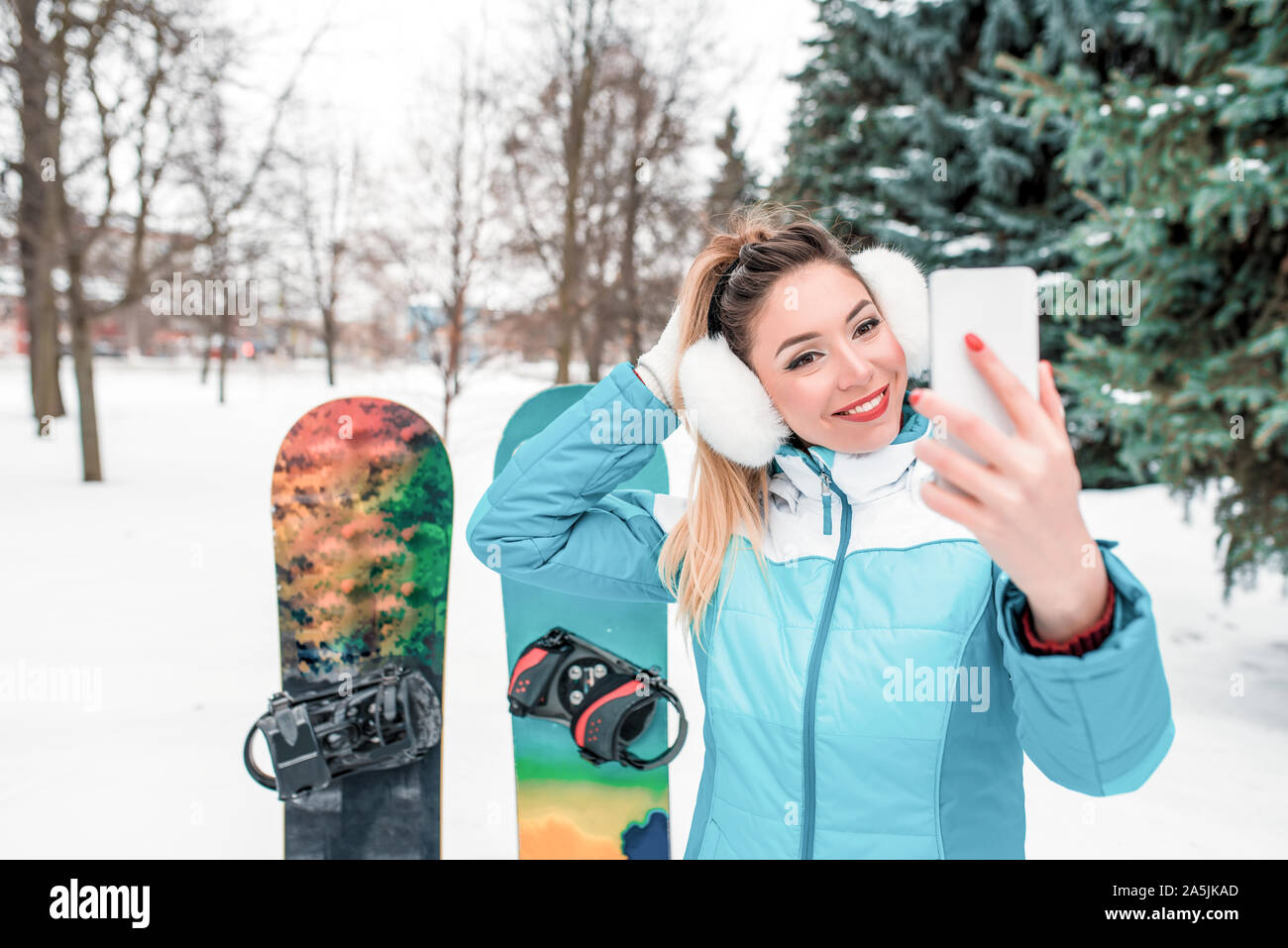 Bella mujer, hablando teléfonos móviles, imágenes selfie llamadas de vídeo. Mono Fondo snowboard nieve, árboles de Navidad. Emociones felicidad Fotografía de stock - Alamy