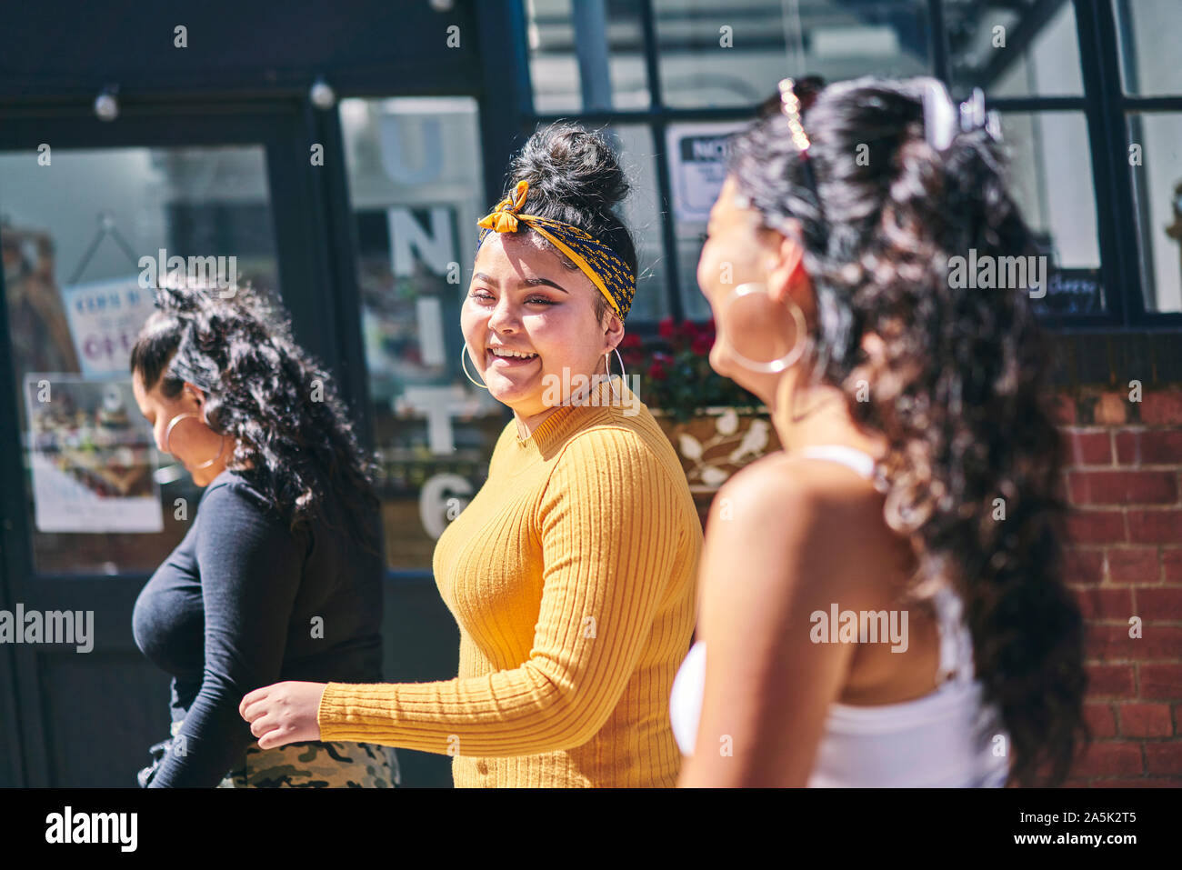 Mujer joven y sus hermanas adolescentes caminar y hablar en la calle Foto de stock