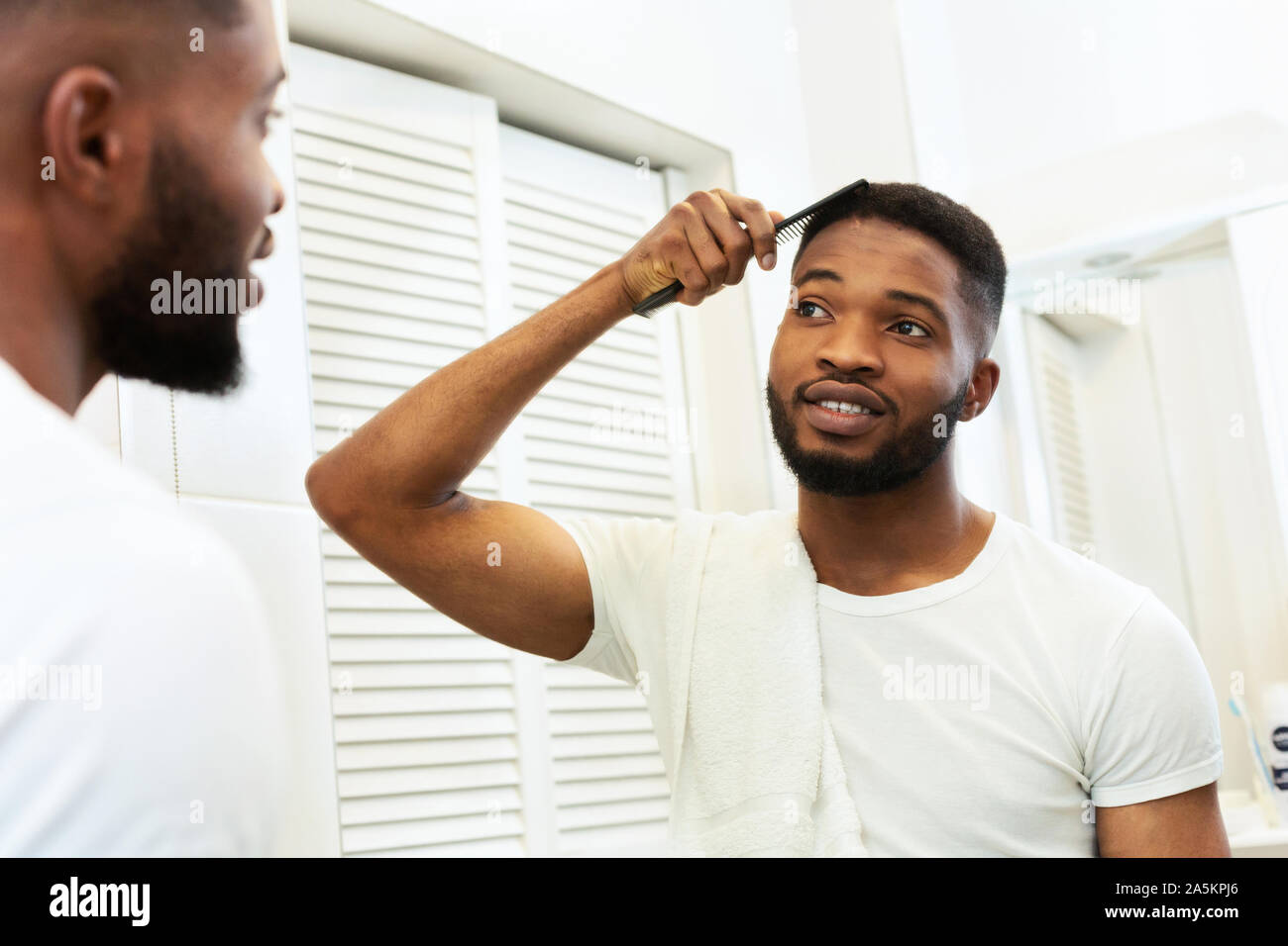 Joven Hombre Afro Peinar Su Cabello Corto Mirando En El Espejo Del Bano Fotografia De Stock Alamy