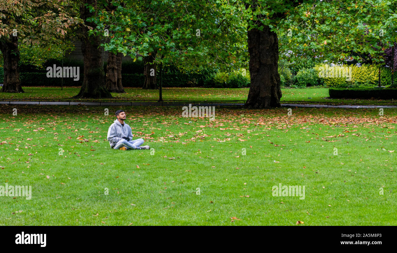 Hombre meditando sobre el césped en park, Dublín, Irlanda, el REINO UNIDO Foto de stock