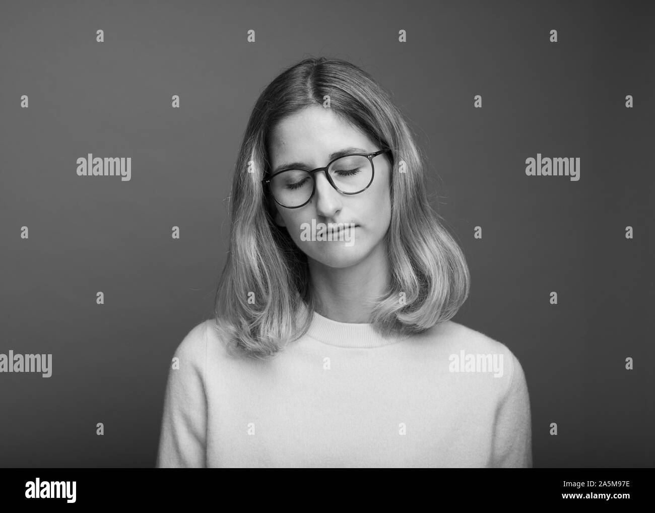 Foto de estudio en blanco y negro de mujer con gafas y con los ojos cerrados Foto de stock