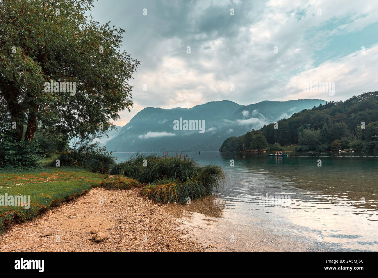 Nublado por la tarde en el lago de Bohinj, Eslovenia. La gente disfruta de las actividades del deporte de agua al aire libre en condiciones de mal tiempo Foto de stock