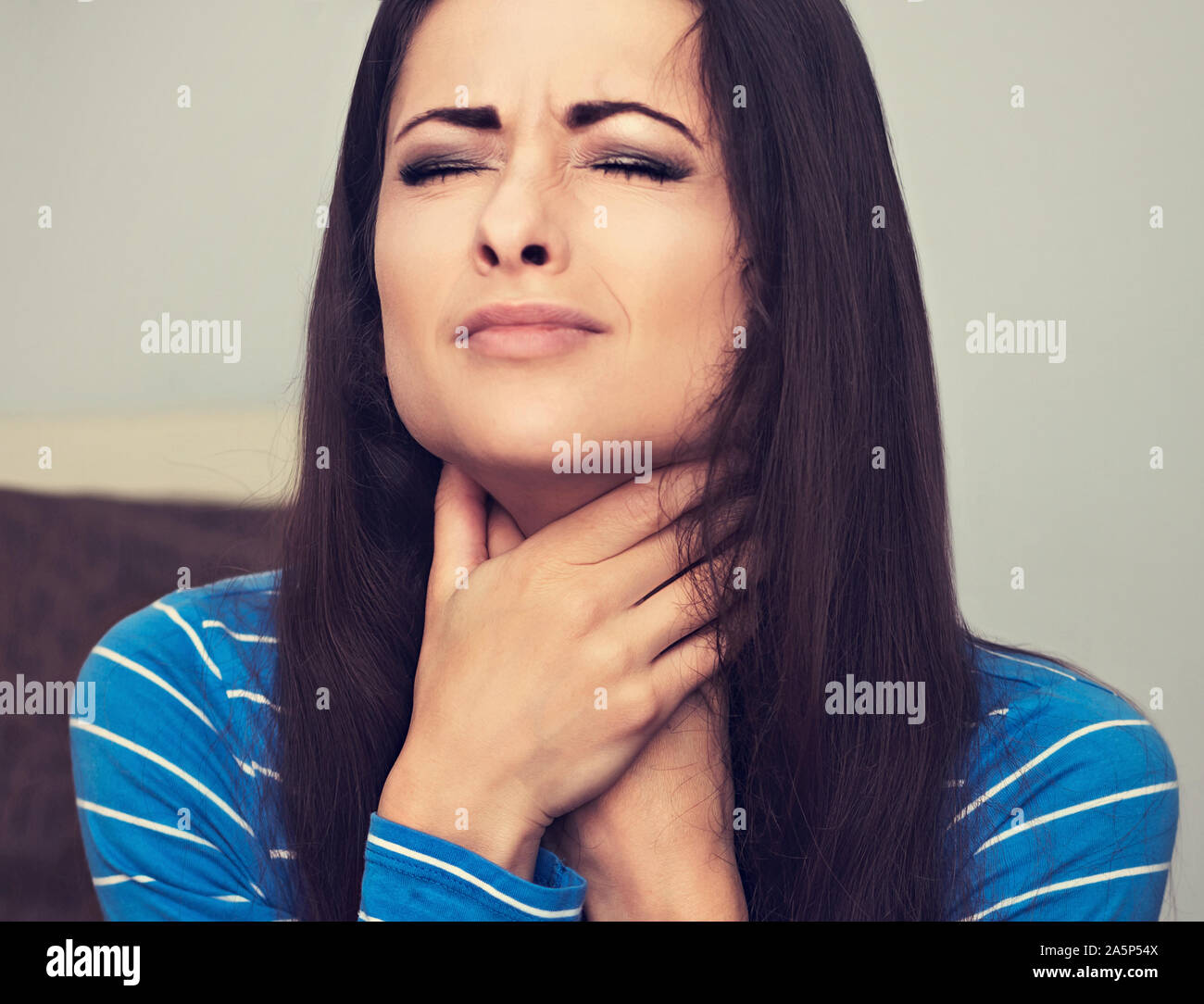 Infeliz mujer con dolor de garganta manteniendo las manos el cuello. Closeup retrato de persona de negocios. Tonificado closeup retrato Foto de stock