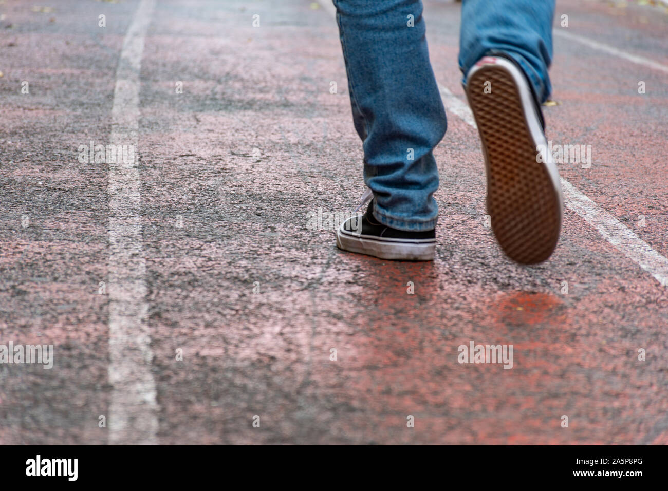 Hombre vestido con pantalones vaqueros y zapatillas de deporte zapatos  caminando en la calle vacía Fotografía de stock - Alamy