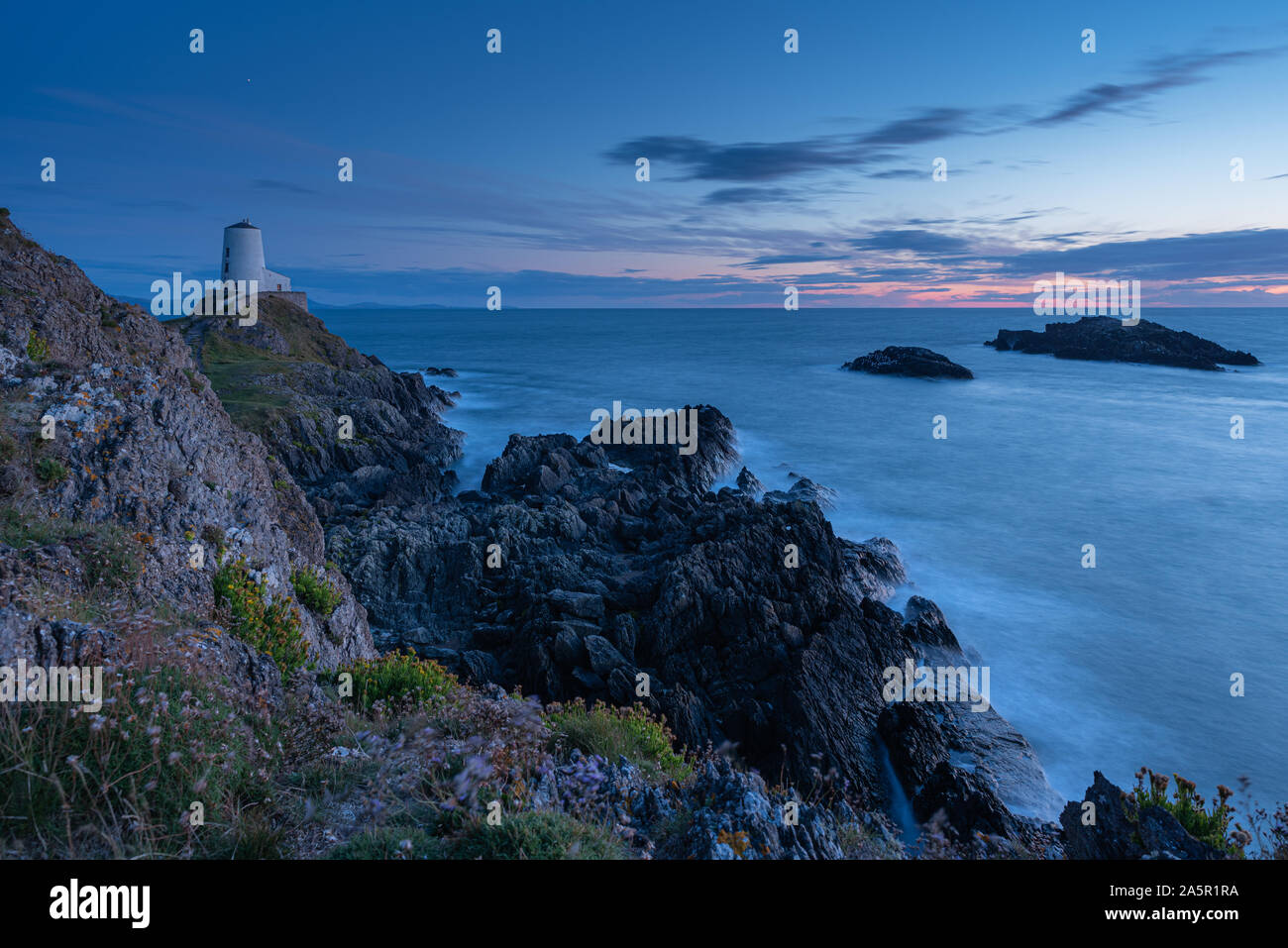 El faro de la isla Llanddwyn, Twr Mawr en Ynys Llanddwyn en Anglesey, Gales del Norte en la hora azul Foto de stock