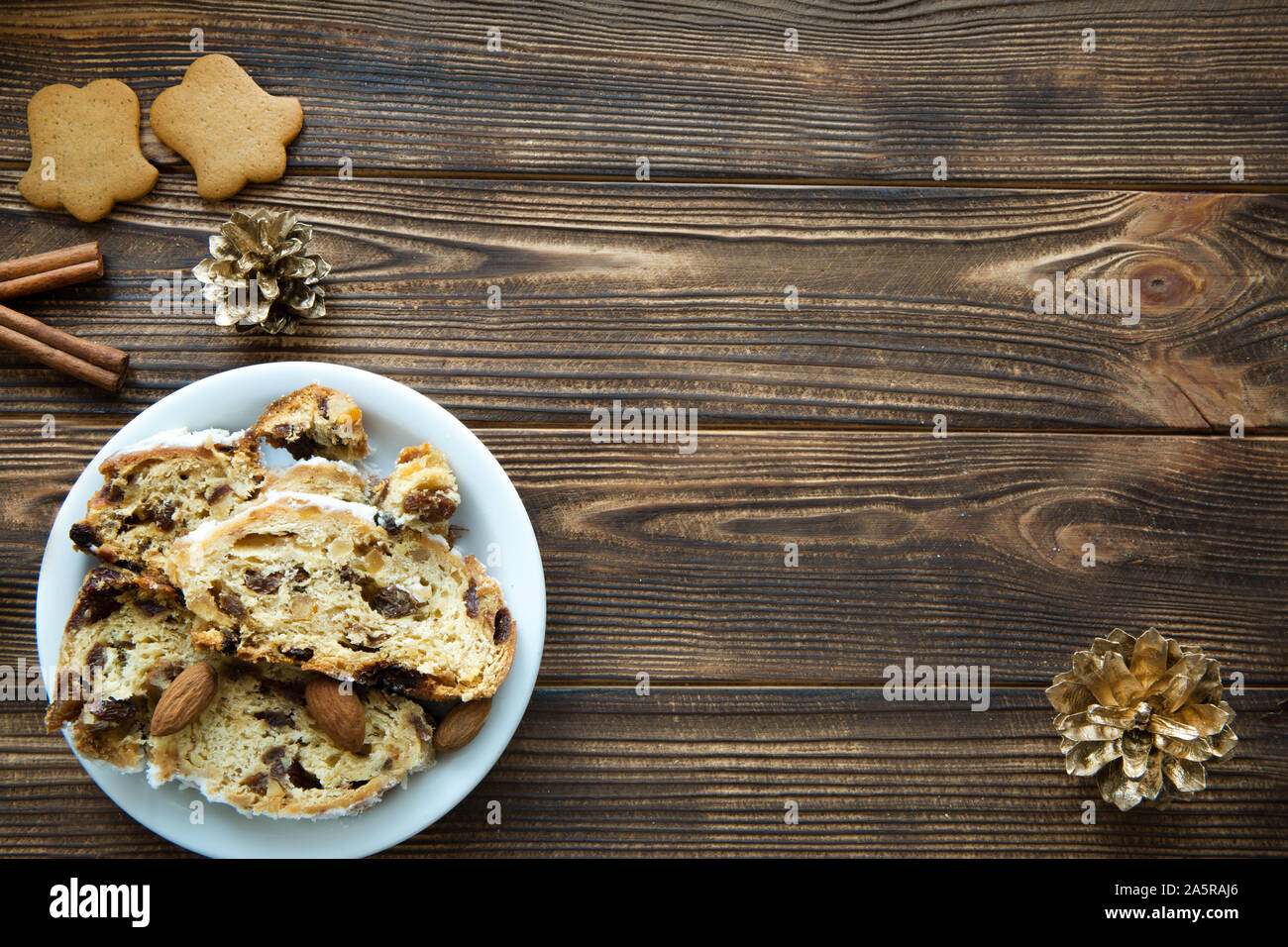 Pastel de Navidad y gingerbread cookies en tabla de madera marrón. Conos de oro y canela decoraciones. Espacio libre para el texto. Espacio para un saludo Foto de stock