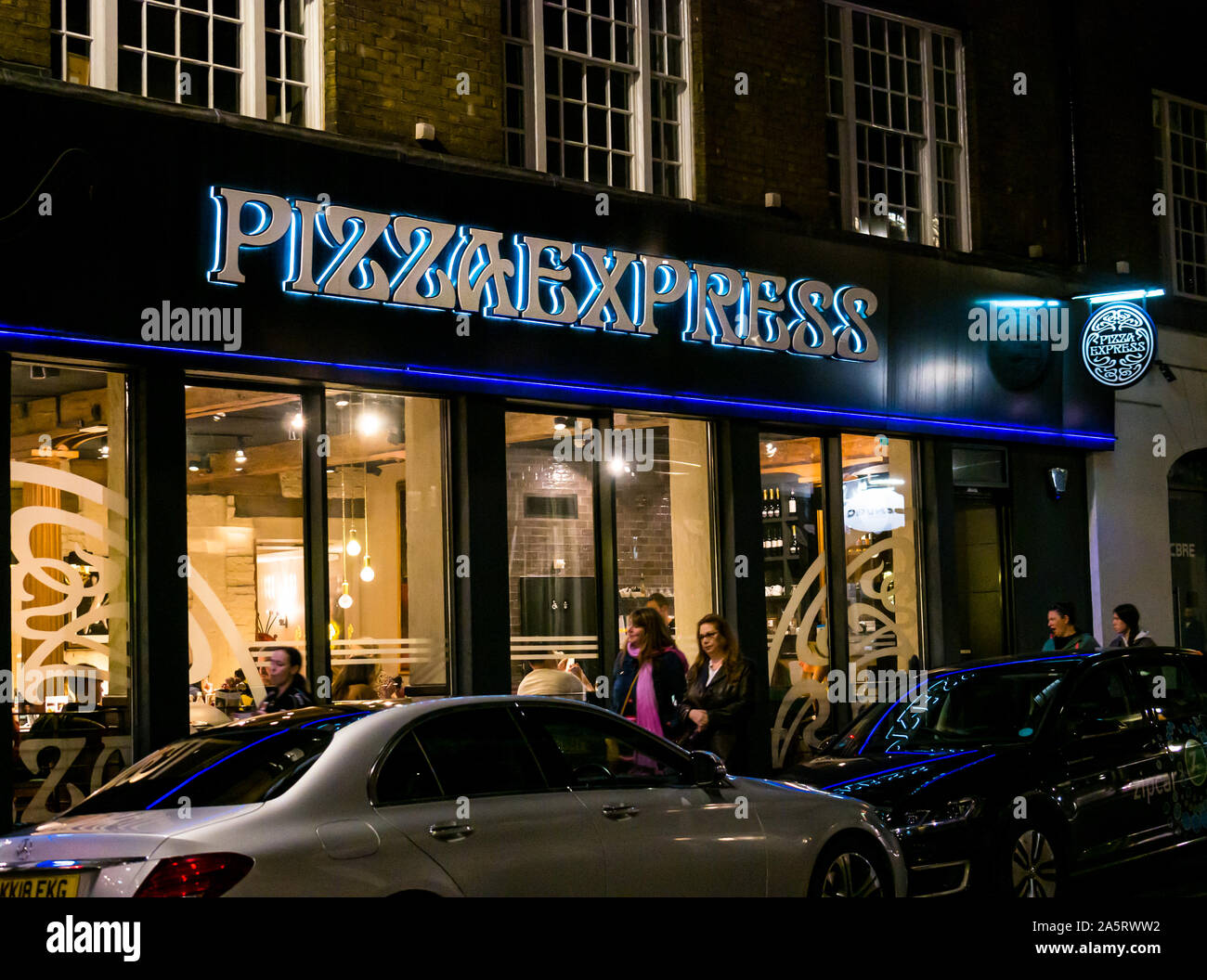 El restaurante Pizza Express ventana frontal iluminado por la noche, Londres, Inglaterra, Reino Unido. Foto de stock