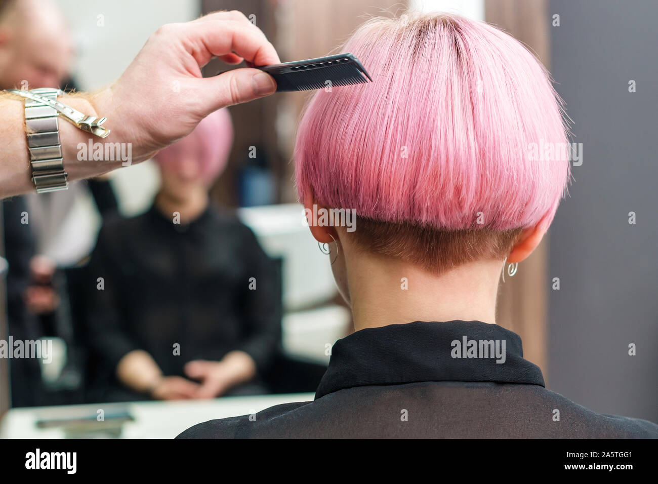 La peluquería está usando peine el pelo rosa para mujeres en un salón de  belleza. Lado masculino es el peinado mujer corta pelo de color rosa en la  peluquería Fotografía de stock -