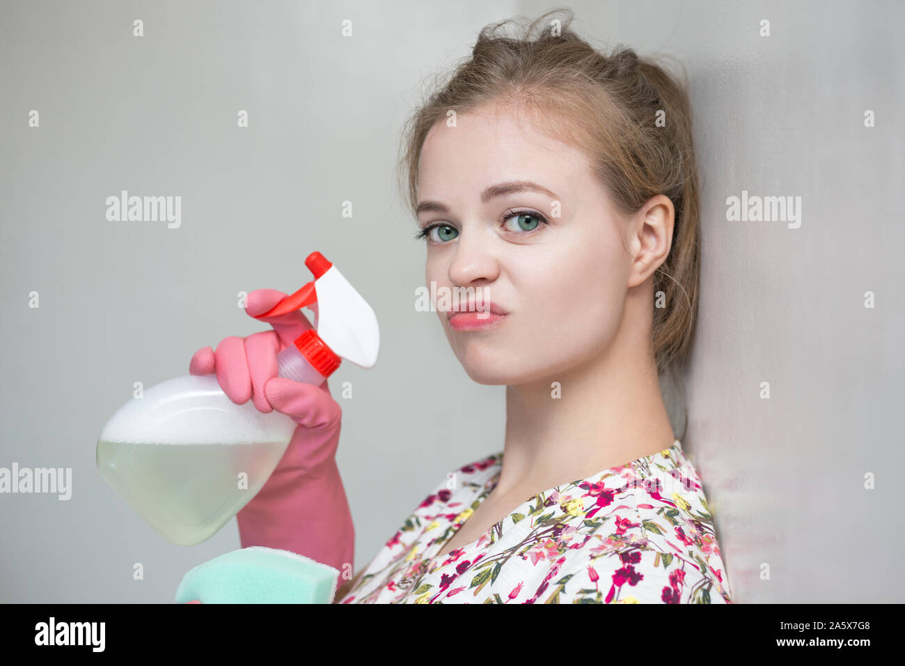 Chica caucásica joven mujer con guantes de goma y la pulverizadora, limpieza de la casa Foto de stock