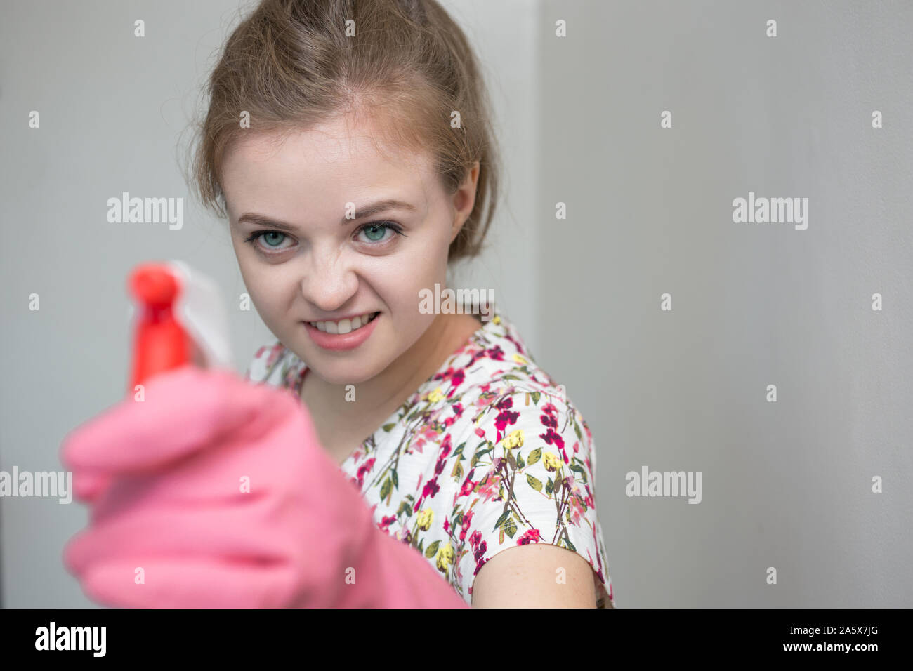 Chica caucásica joven mujer con guantes de goma y la pulverizadora, limpieza de la casa Foto de stock
