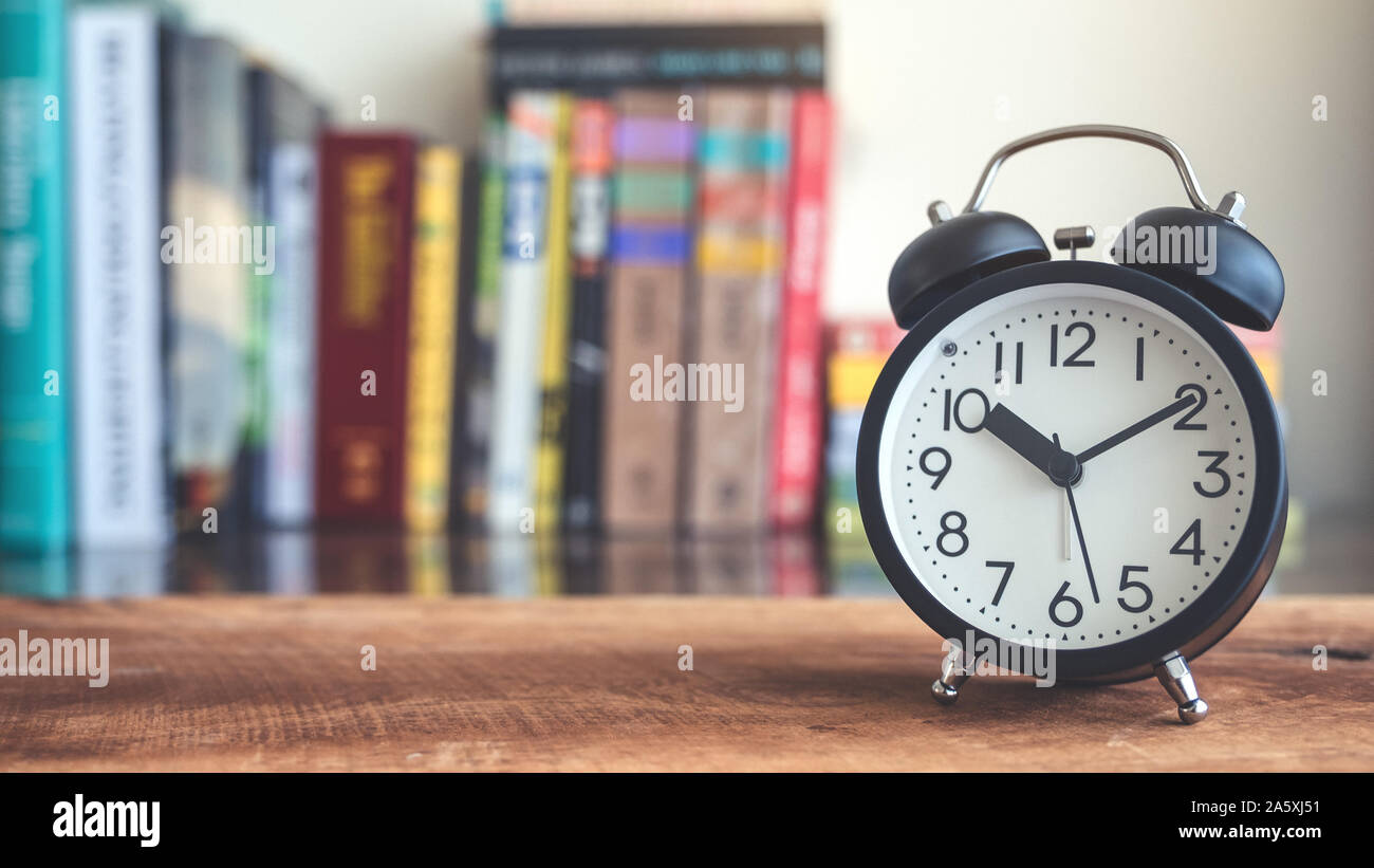 Imagen de primer plano de un reloj despertador negro sobre la mesa de  madera con estantería de desenfoque de fondo Fotografía de stock - Alamy