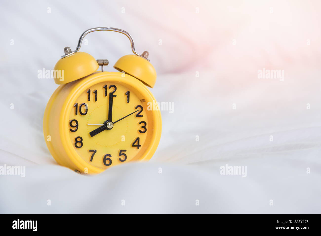 Reloj de alarma amarilla a las 8 am en la cama para despertarse Fotografía  de stock - Alamy