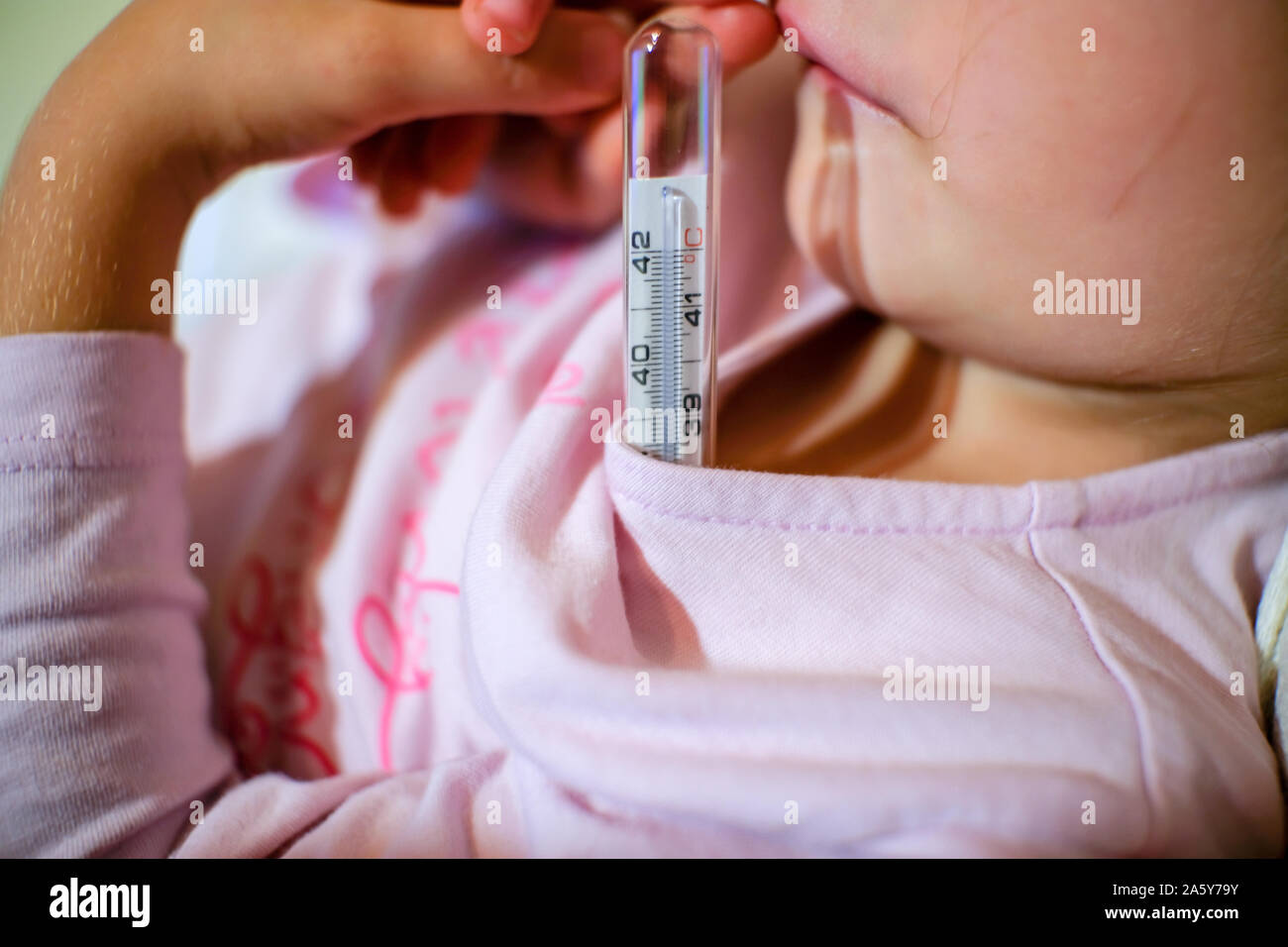 Medir la fiebre con un termómetro de temperatura a un pequeño niño niña, cuidado de la salud Foto de stock