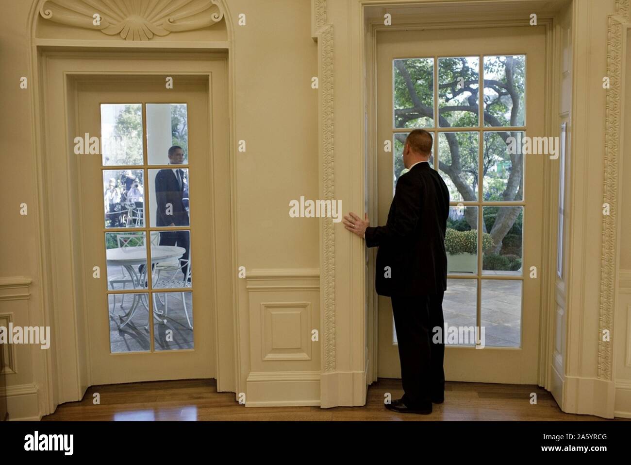 Agente del servicio secreto estadounidense en la oficina oval, se prepara para abrir una puerta como el presidente Obama enfoques Foto de stock