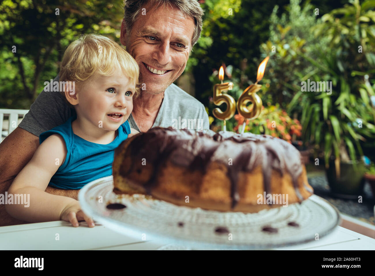 Chico sentado en el regazo del padre, celebrando su cumpleaños Foto de stock