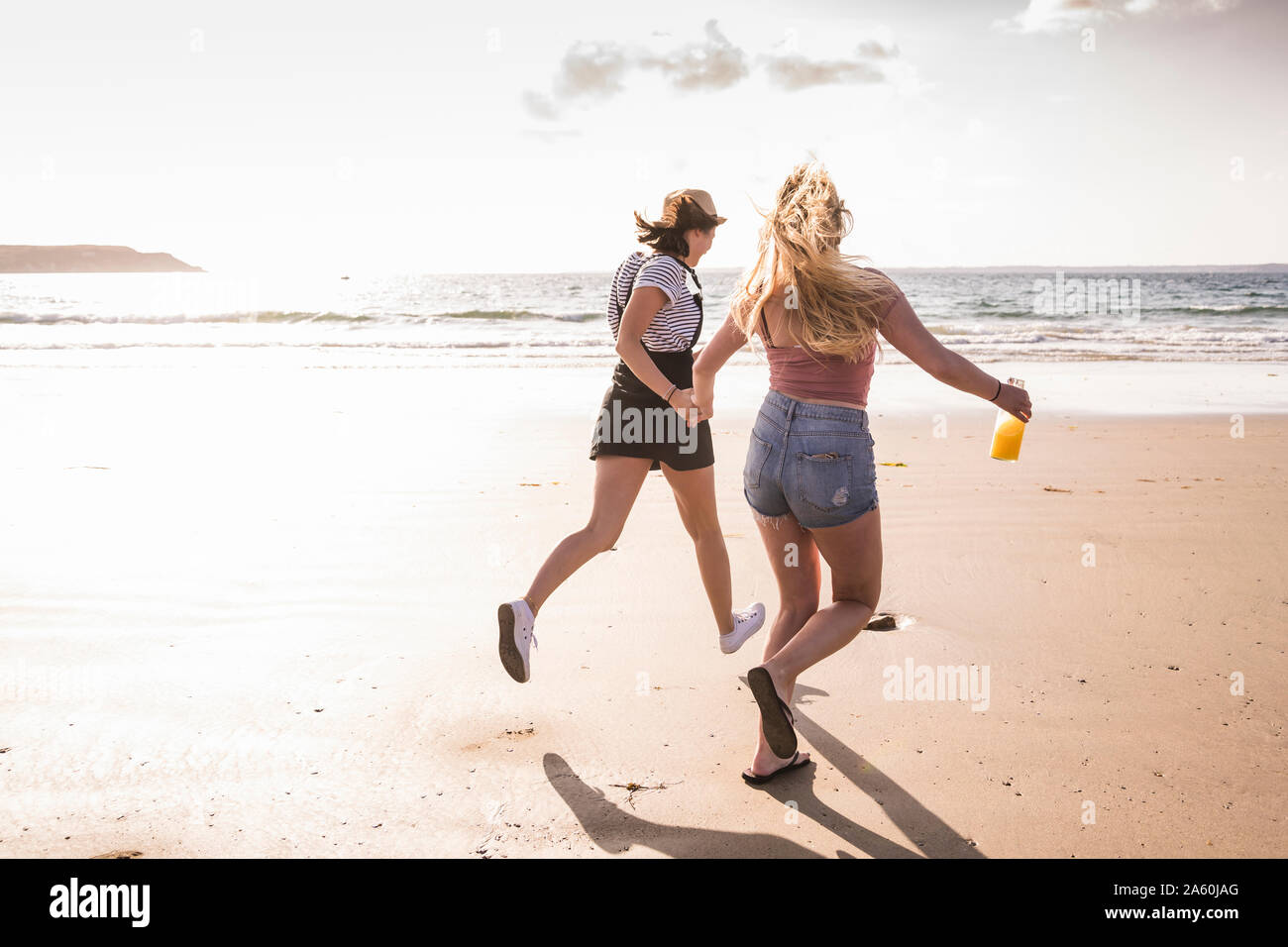 Dos amigas se divierten, correr y saltar en la playa Foto de stock