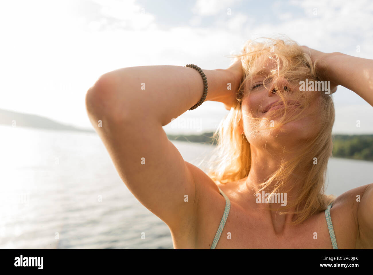 Mujer joven con cabello alborotado en un lago Foto de stock