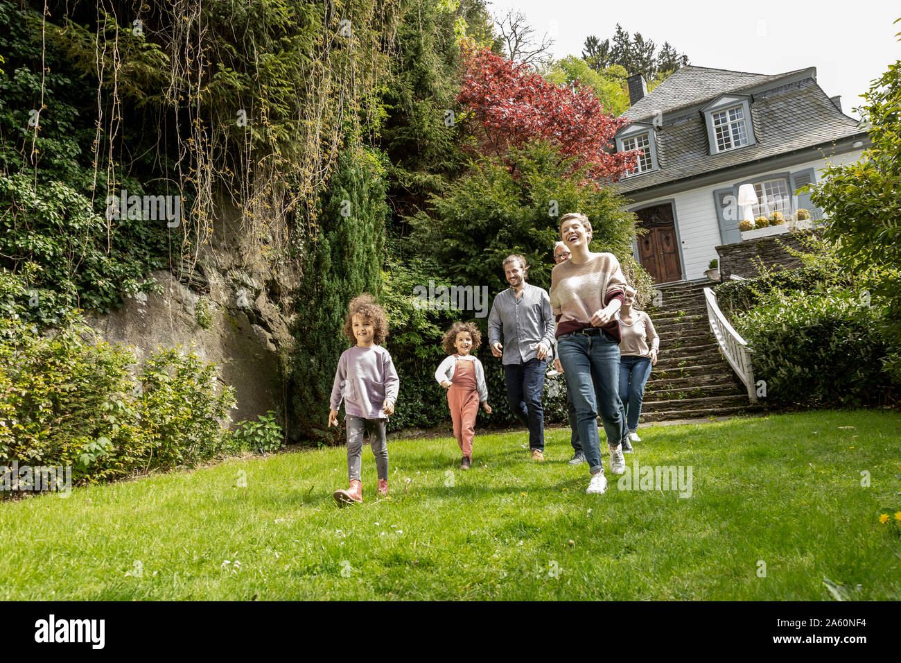 Feliz familia extendida caminando en el jardín de su casa Foto de stock