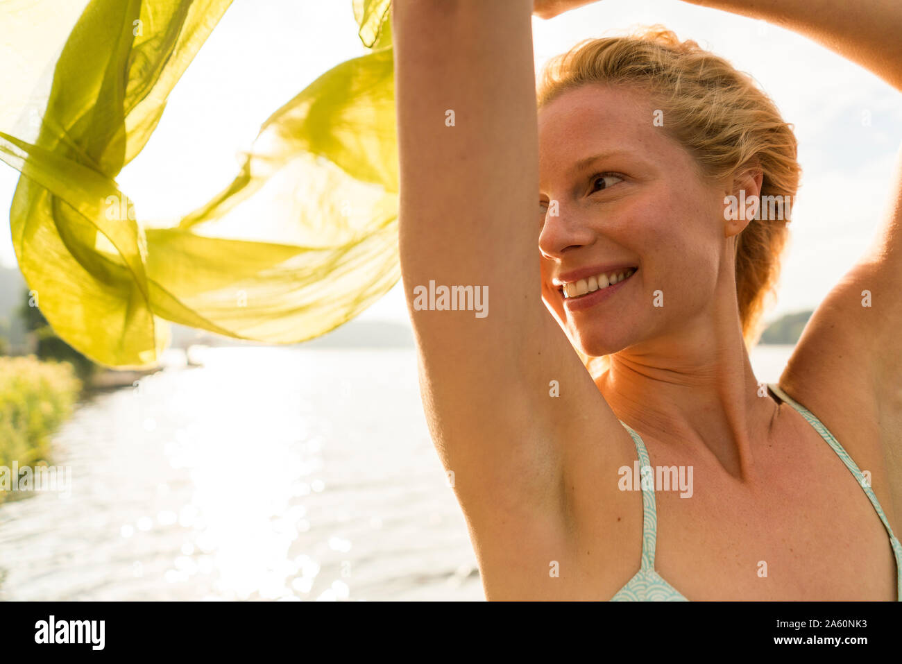 Mujer sonriente sosteniendo un paño en un lago Foto de stock