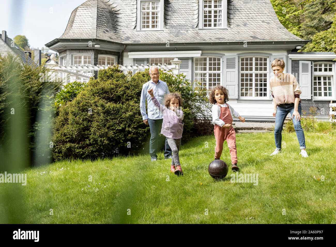 Familia feliz jugando al fútbol en el jardín Foto de stock