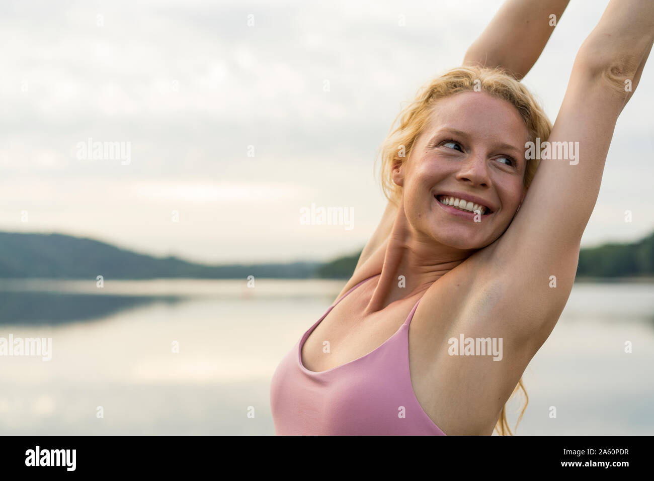 Feliz joven elevando sus brazos en un lago Foto de stock