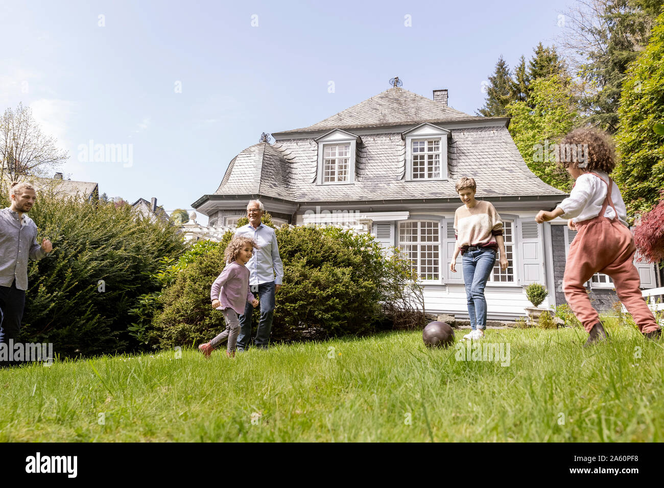 Familia feliz jugando al fútbol en el jardín Foto de stock