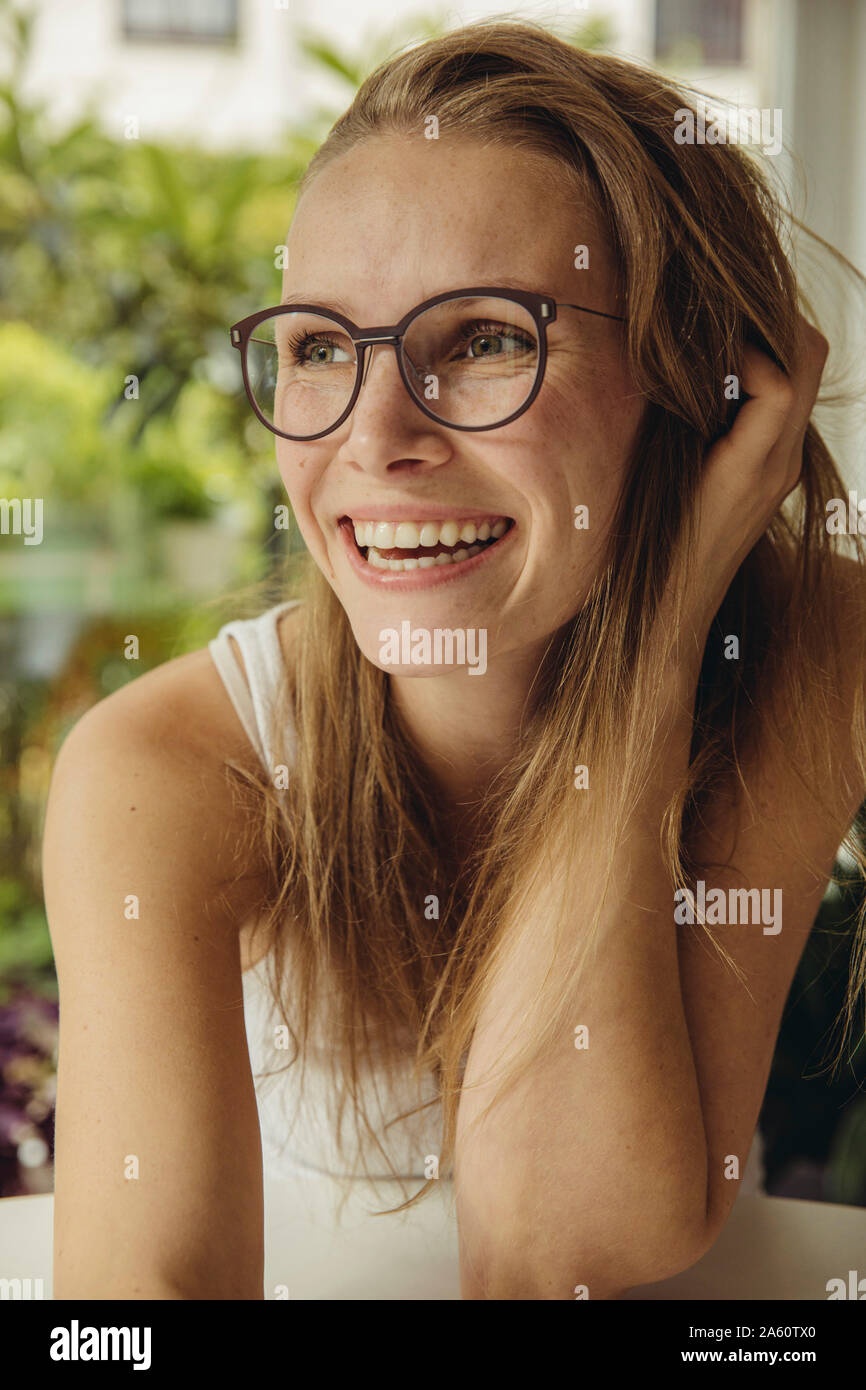 Retrato de mujer joven feliz con gafas mirando lateralmente Foto de stock