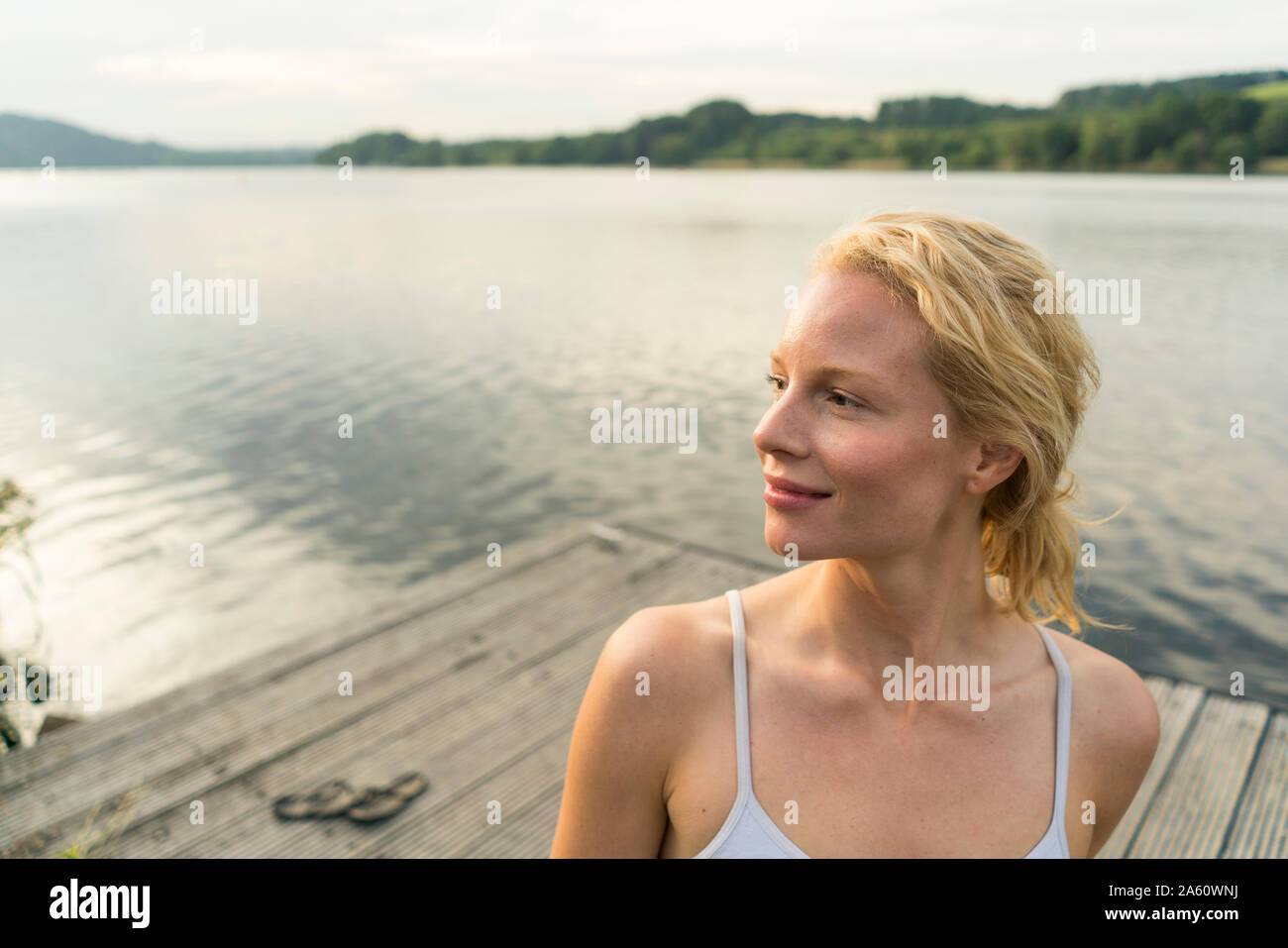 Mujer joven en un muelle en un lago en busca de distancia Foto de stock