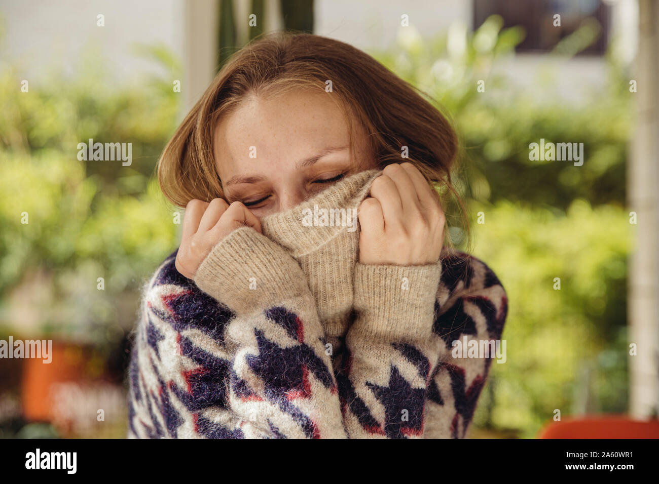 Retrato de mujer joven con los ojos cerrados se hunde en su jersey de lana Foto de stock