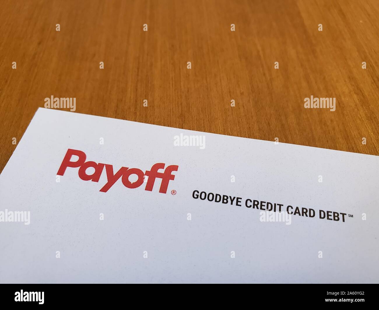 Primer plano del logotipo de la empresa de consolidación de deuda Payoff, con el lema Goodbye De Deuda de tarjeta de crédito, en papel sobre un fondo de madera ligera, 10 de septiembre de 2019. () Foto de stock
