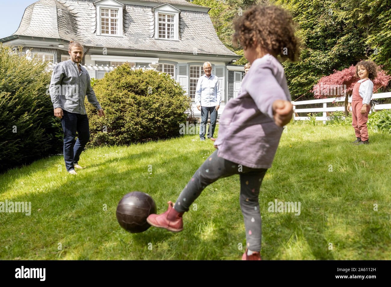 Familia feliz jugando al fútbol en el jardín Foto de stock