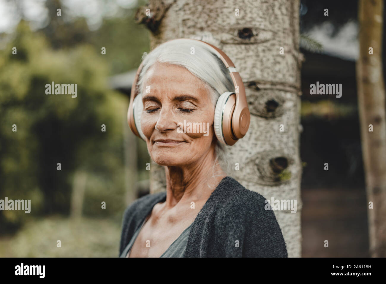 Mujer Senior relajarse en la naturaleza, escuchar música con auriculares Foto de stock