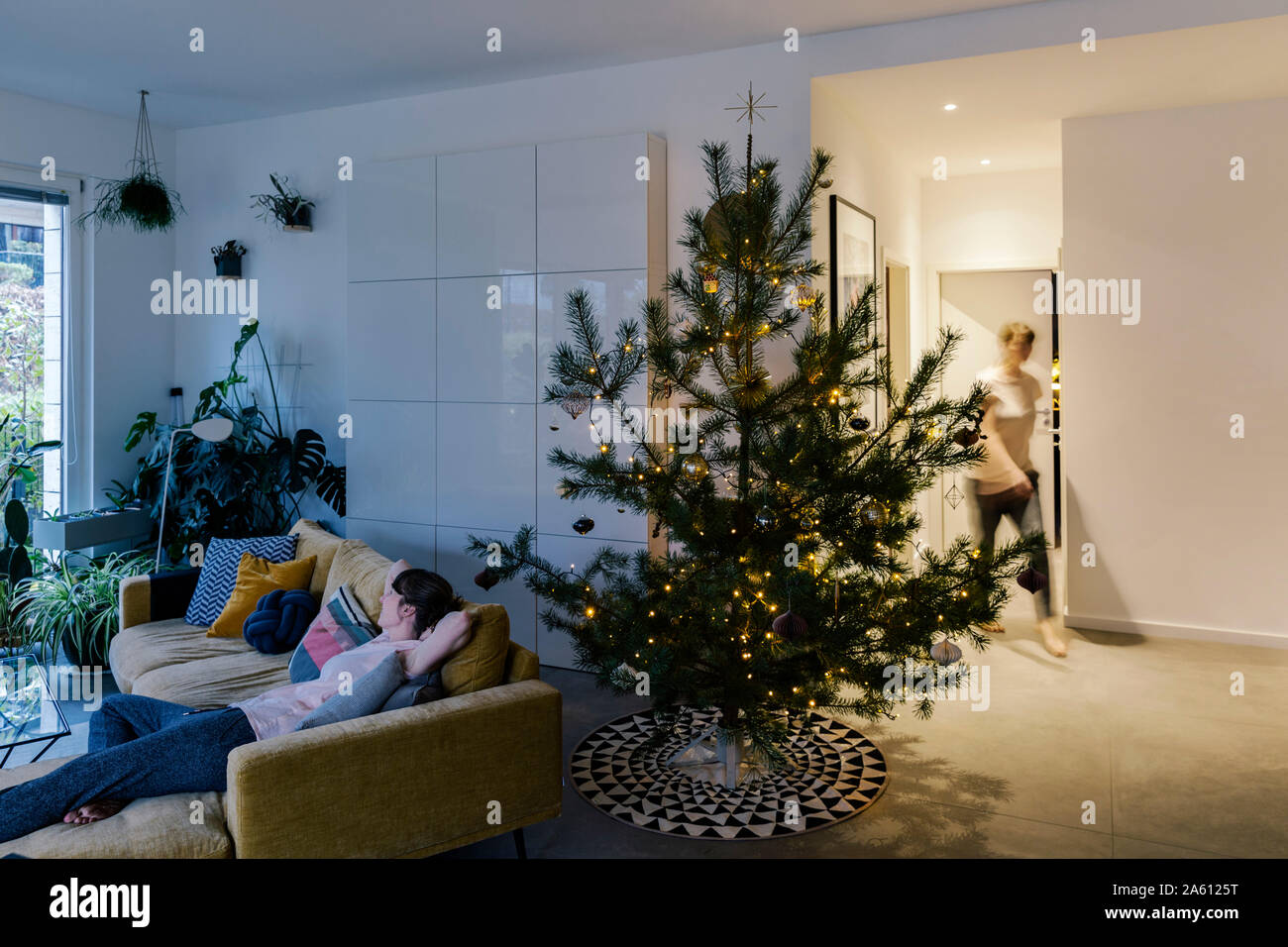 La mujer en el hogar con pino decorado árbol de Navidad en el salón Foto de stock