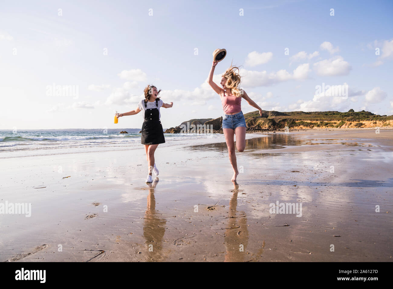 Dos amigas se divierten, correr y saltar en la playa Foto de stock