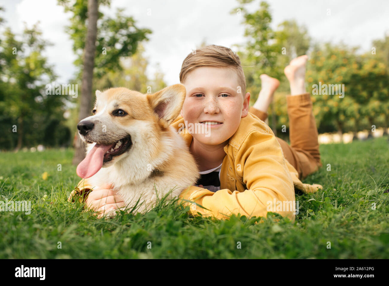 Chico con Welsh Corgi Pembroke en un parque Foto de stock