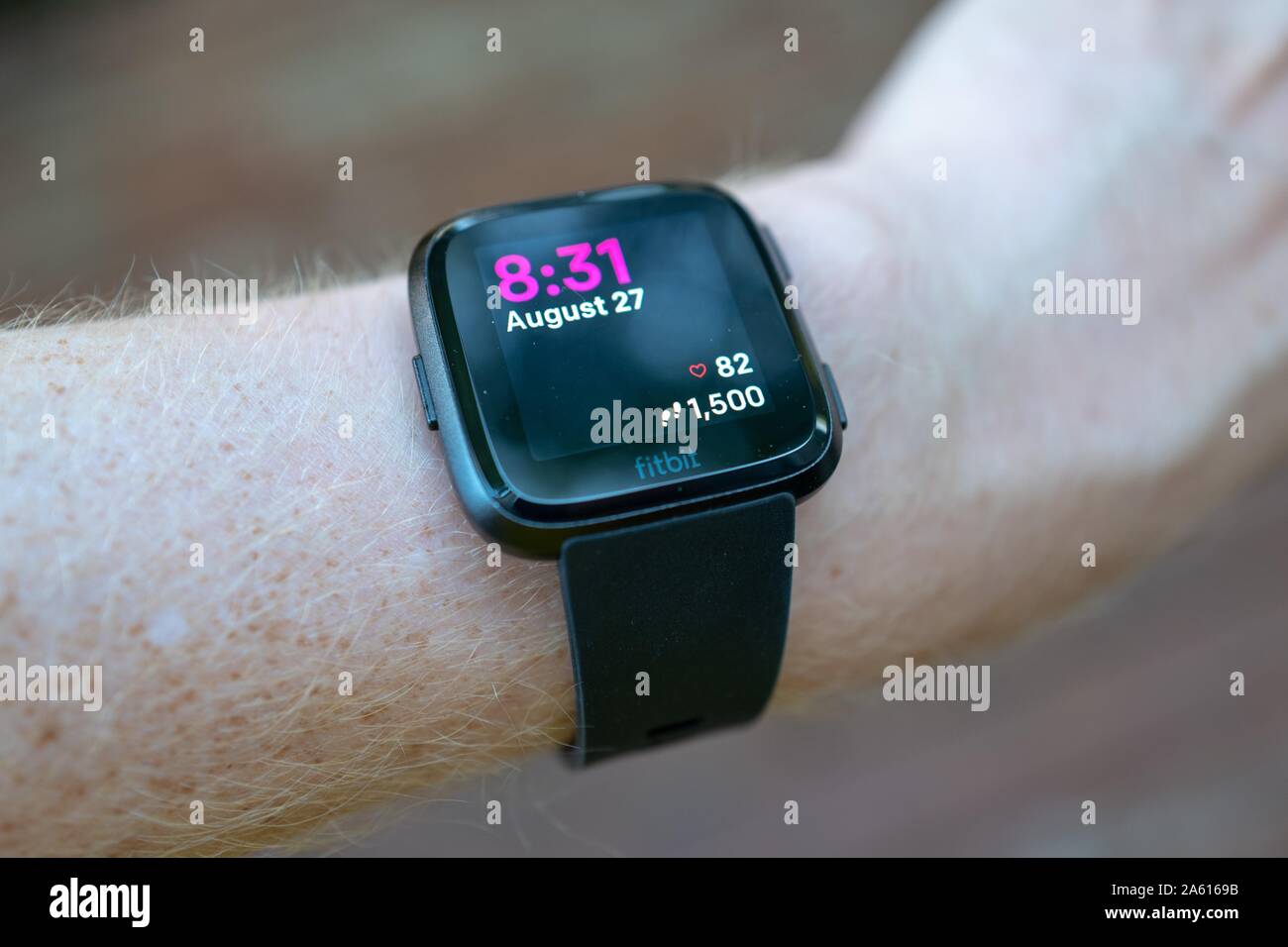 Primer plano de la muñeca de un hombre que lleva el reloj inteligente Fitbit Versa, San Ramón, California, mostrando la frecuencia cardiaca y el recuento de pasos, 27 de agosto de 2019. () Foto de stock