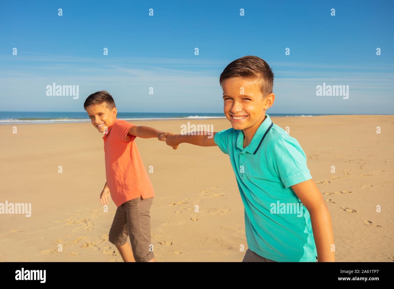 Dos niños juegan en la playa corriendo tirando de manos Foto de stock