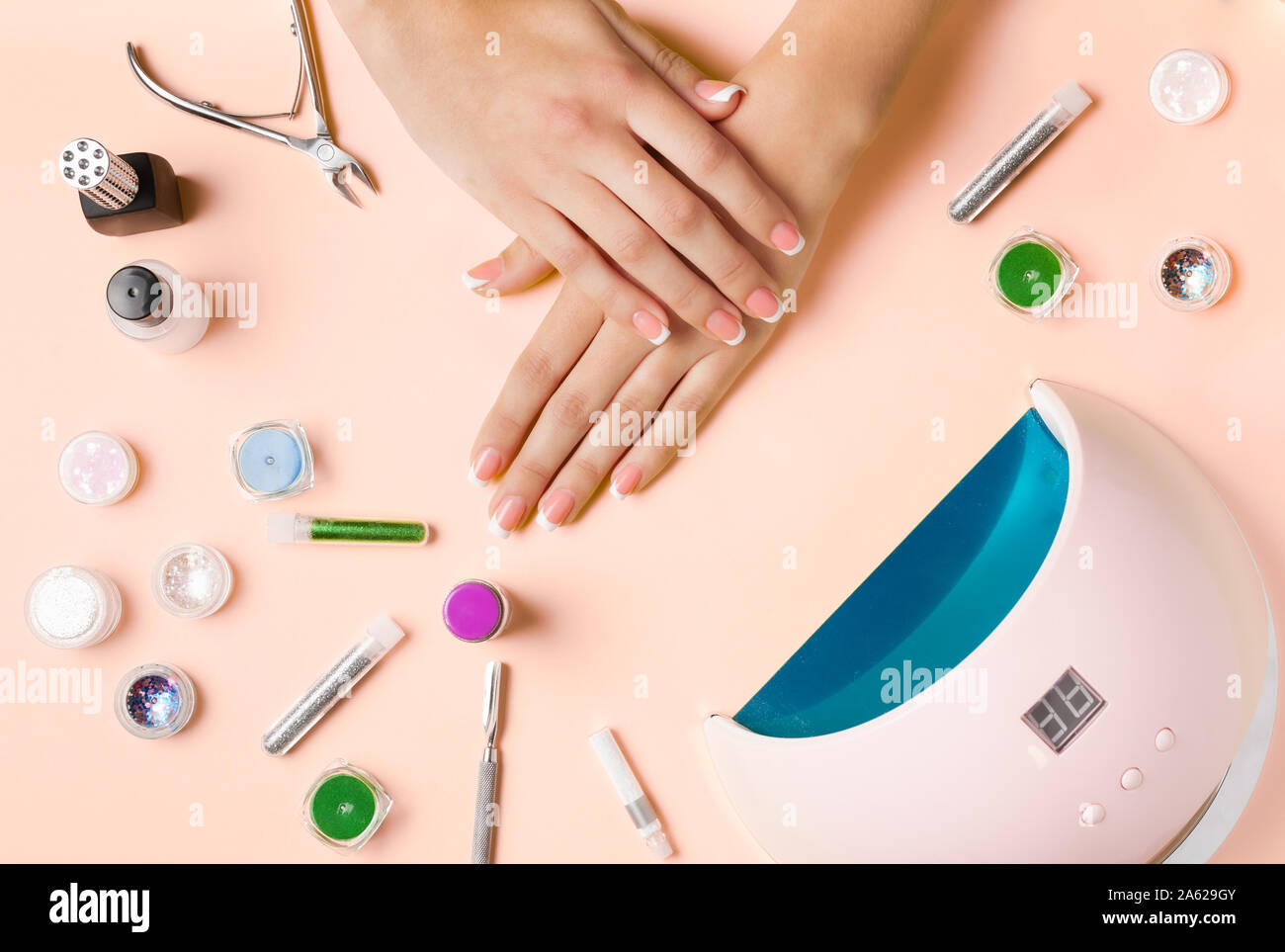 Composición para el cuidado de las uñas, mujeres jóvenes las manos,  manicura francesa, polaca, Lámpara de Gel para uñas y equipos para el  cuidado de las uñas. Foto laicos plana Fotografía de