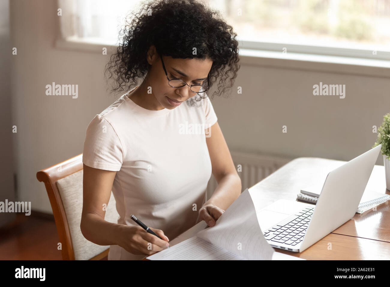 Concentrado afroamericano joven mujer de negocios que la firma de los documentos, los seguros médicos. Foto de stock