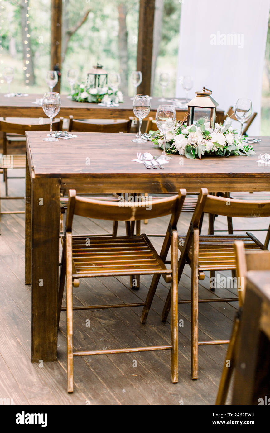 Boda estilo rústico. Decoración de la mesa de bodas. Mesa de madera  decorada por cuchillos y tenedores, wineglasses, vegetación y flores con  linterna de oro Fotografía de stock - Alamy