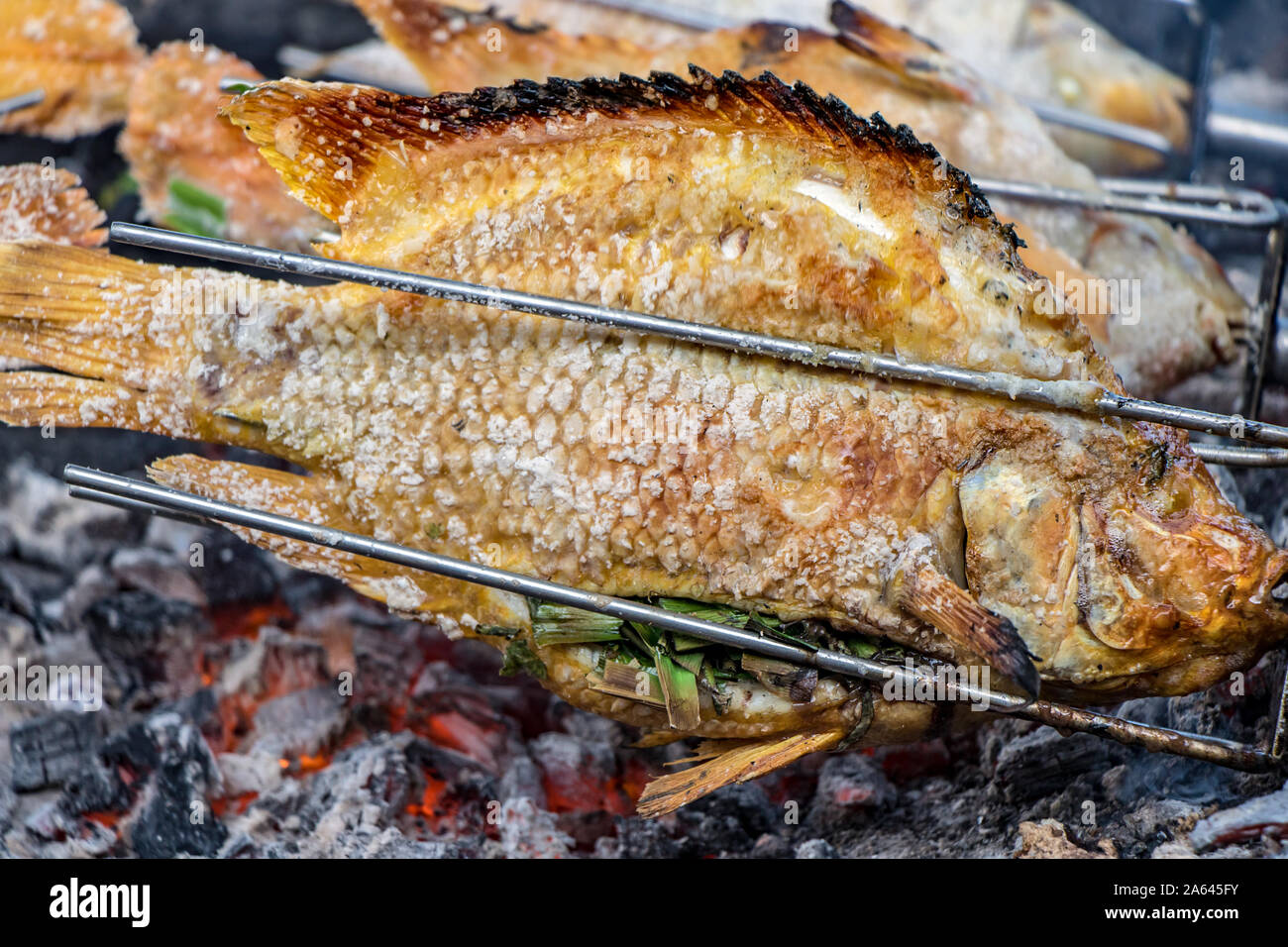 Asar pescado sobre el carbón, el restaurante de la calle, Tailandia.  Preparar pescado asado sobre la rotación de las agujas, de cerca Fotografía  de stock - Alamy