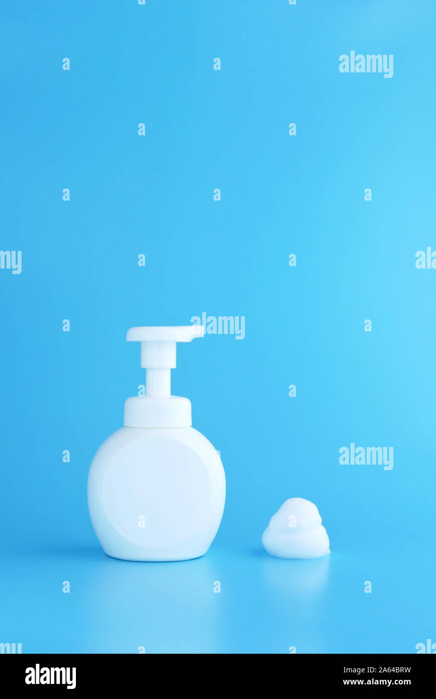 Botella de bomba de plástico y mousse espuma o espuma limpiadora aislado sobre fondo azul, con copia espacio vertical concepto de limpieza. Foto de stock