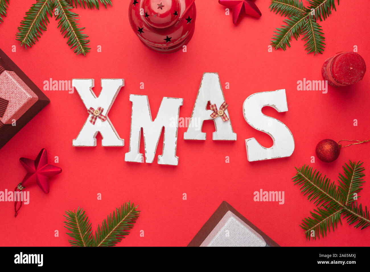 Letras decorativas navideñas rodeado con adornos de Navidad y regalos. Navidad, Año Nuevo composición sobre la superficie roja. Sentar planas, vista superior. Foto de stock