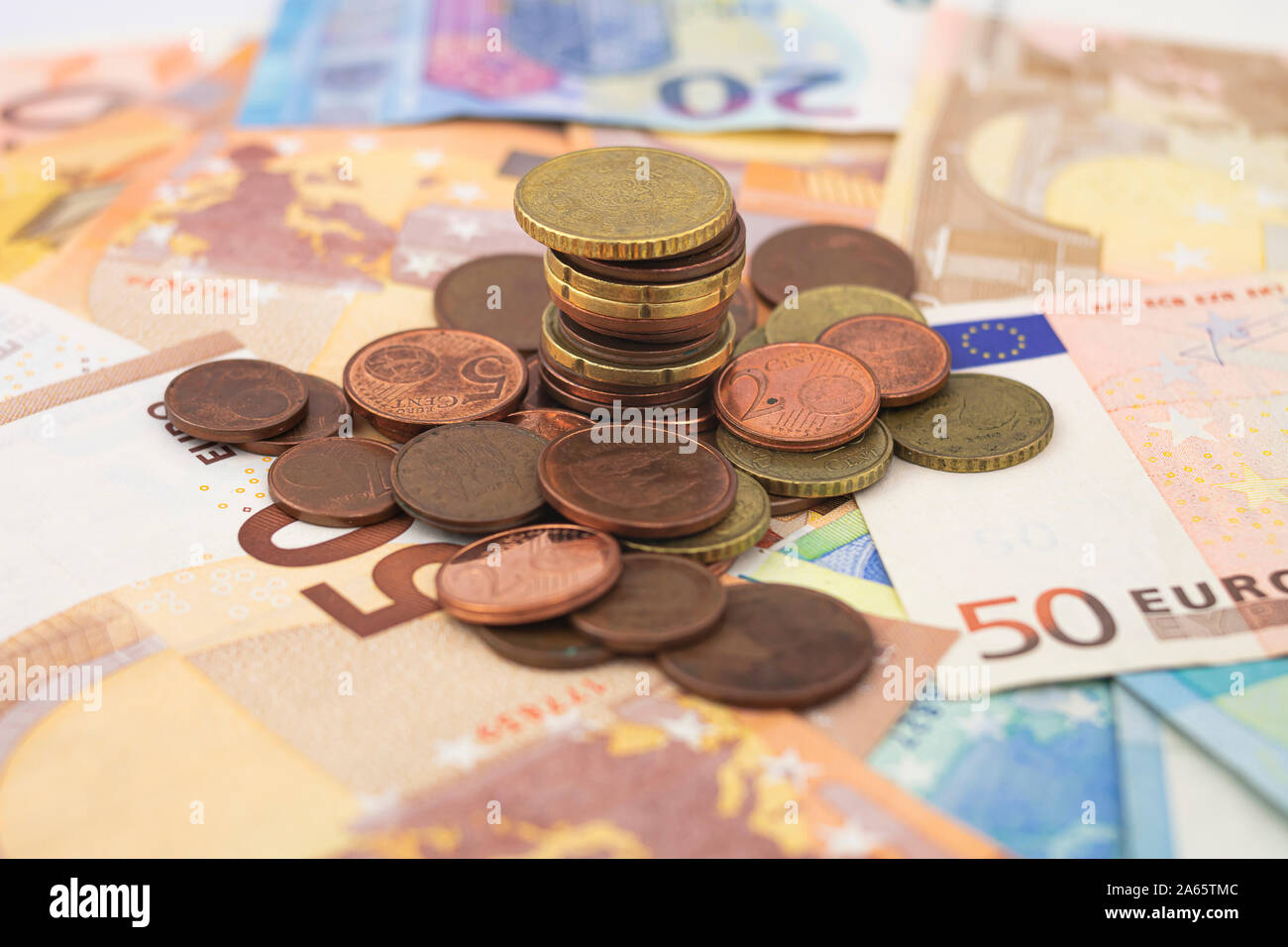 Un montón de monedas en euros distribuidos en cincuenta y veinte euros billetes en euros Foto de stock