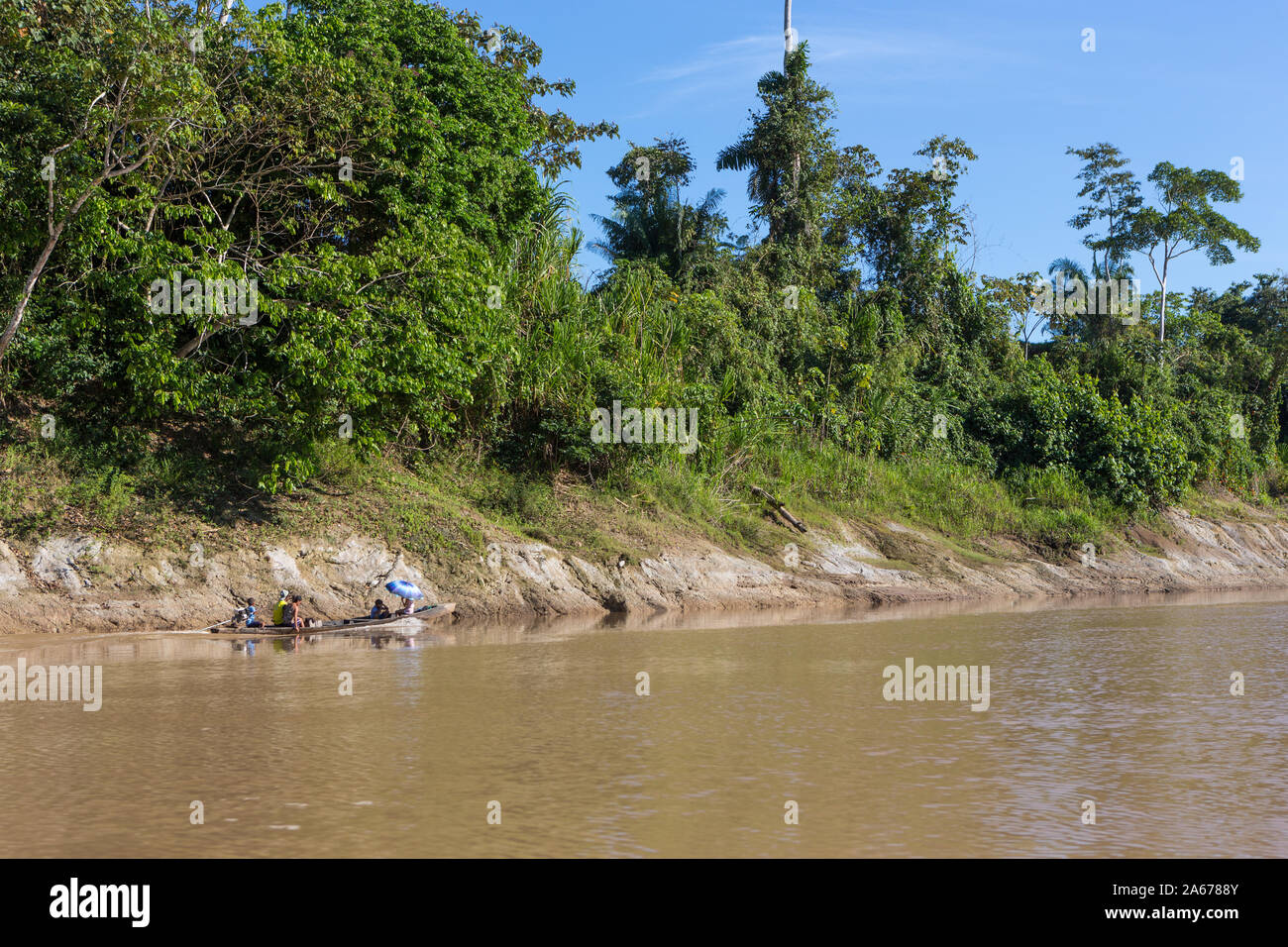 Vista del motor barcos de madera rústica con la gente local sobre el río Purus en Amazon en un día soleado de verano, con árboles en la ribera del río y cielo azul. Foto de stock