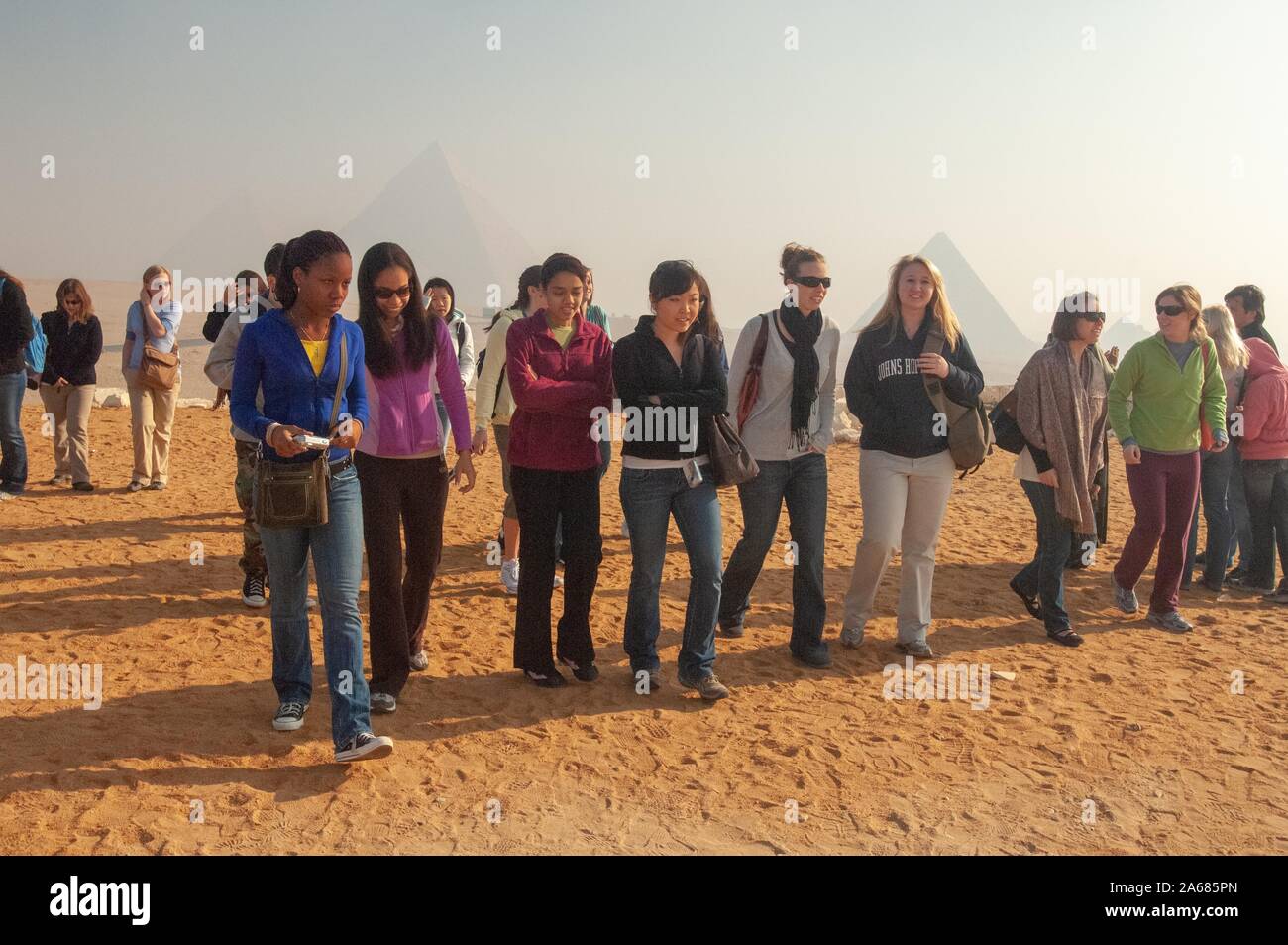Un grupo de estudiantes de la Universidad Johns Hopkins, afuera en un día soleado, caminando hacia la cámara con varias pirámides, visible en la distancia, en Giza, Egipto durante un programa de estudios en el extranjero, 7 de enero de 2008. Desde el Homewood Fotografías. () Foto de stock