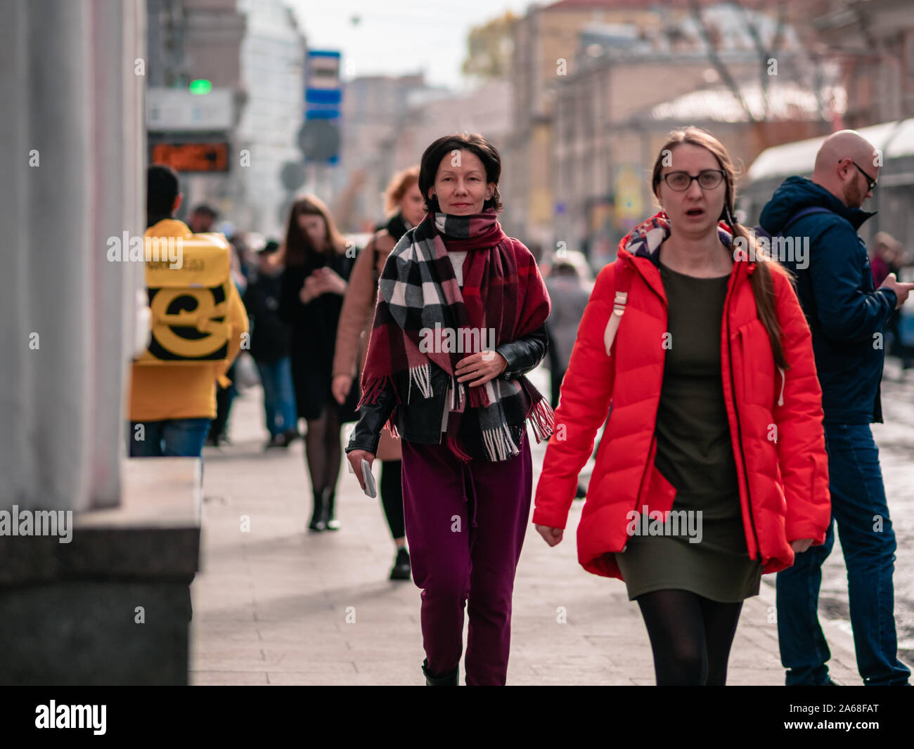 Moscú, Rusia 19 de octubre de 2019: Una mujer bufanda camina en medio de una multitud de personas vestidas de demi-ropa temporada a lo largo de la calle. Otoño cálido